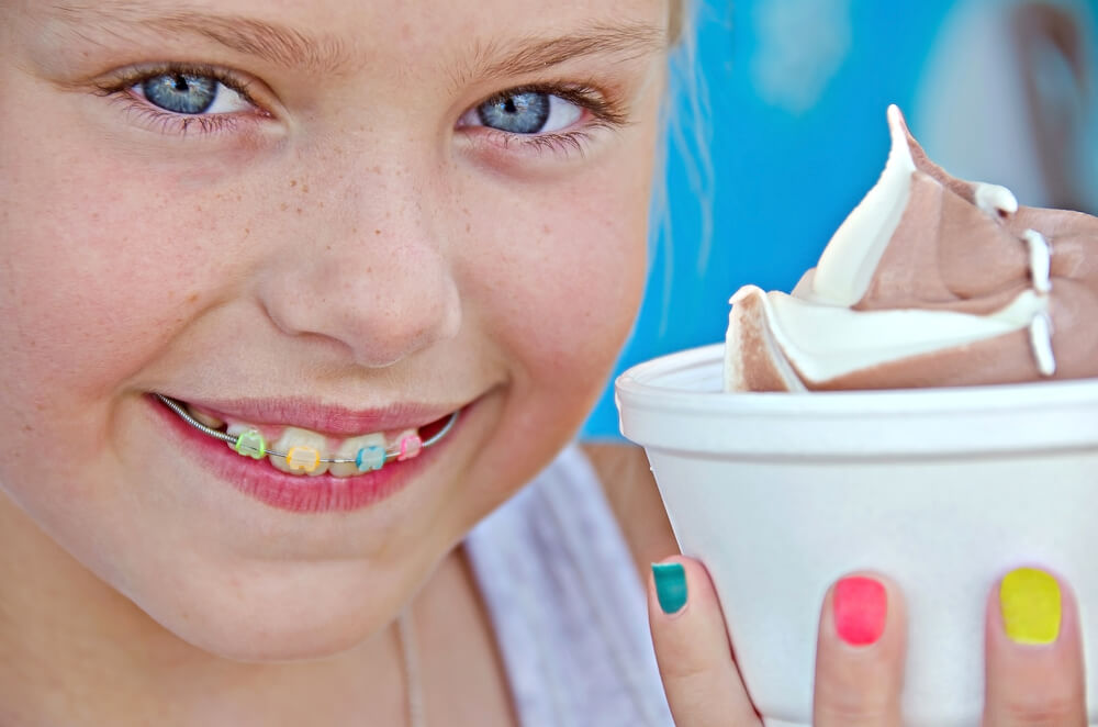 Girl smiling with colored braces and ice cream